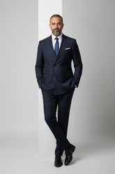 Man wearing navy pinstripe double-breasted suit with tailored fit and matching tie.